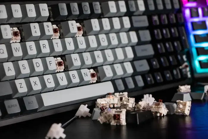 A mechanical keyboard with keycaps removed and switches and stabilisers strewn about.